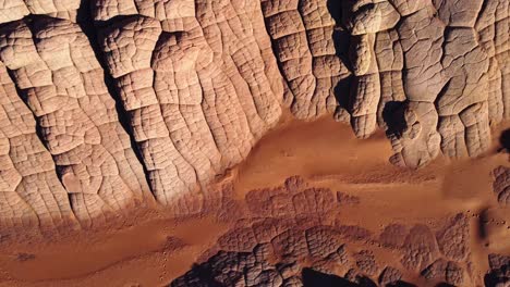 Rocky-cliffs-and-sandy-ground-on-sunny-day-in-desert-terrain