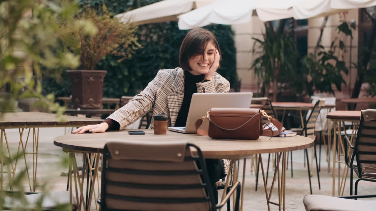 mujer de negocios trabajando en una computadora portátil en un café al aire libre.