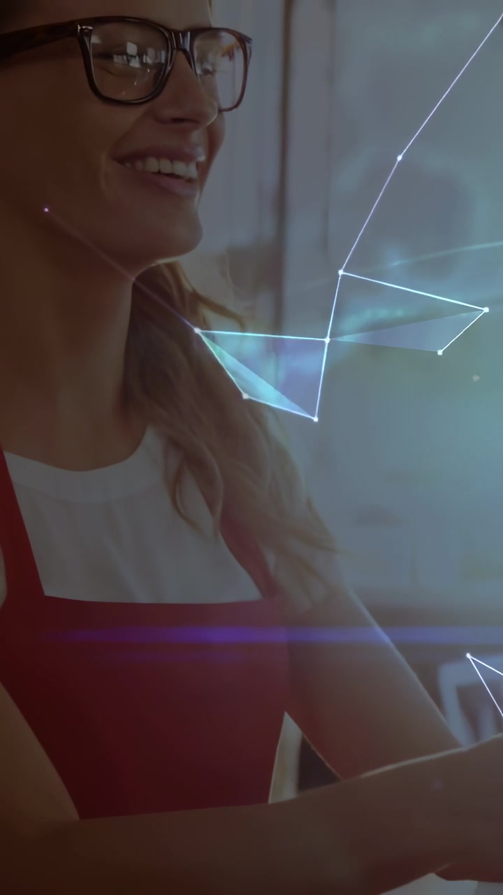 Video verticale: Donna con grembiule rosso che segue ologrammi che appaiono e si muovono verso destra, mostrando tecnologia.