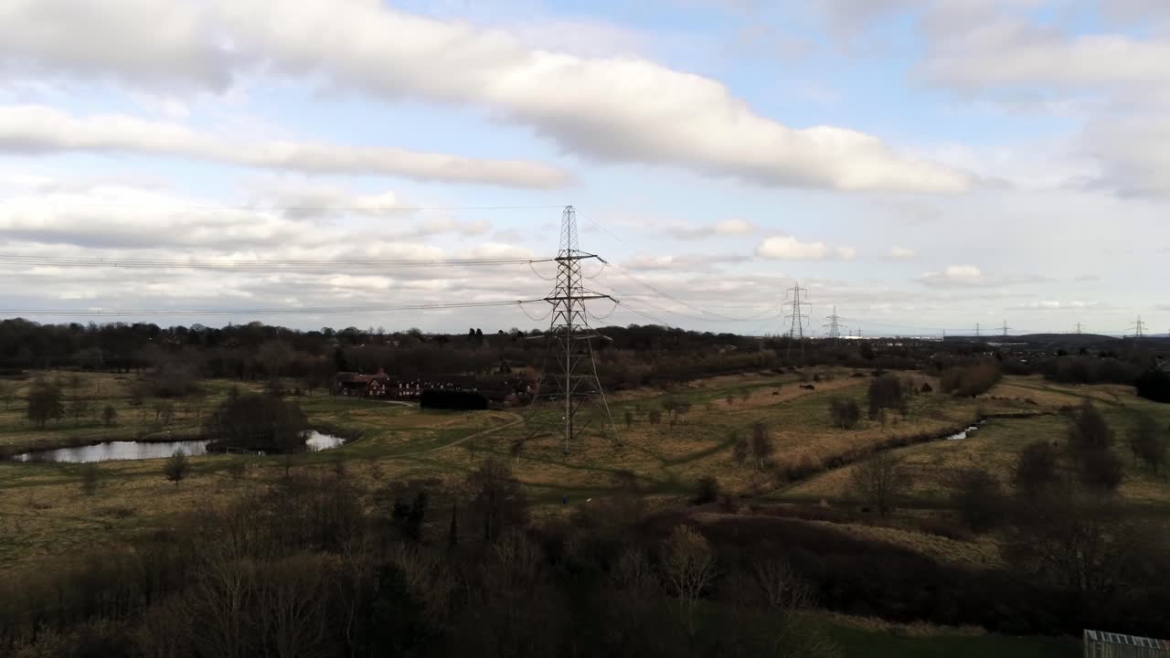 Electricity distribution power pylon overlooking British parkland countryside, Aerial push in view