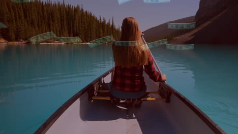 vista trasera de una mujer navegando en un lago contra billetes de dólar estadounidense cayendo