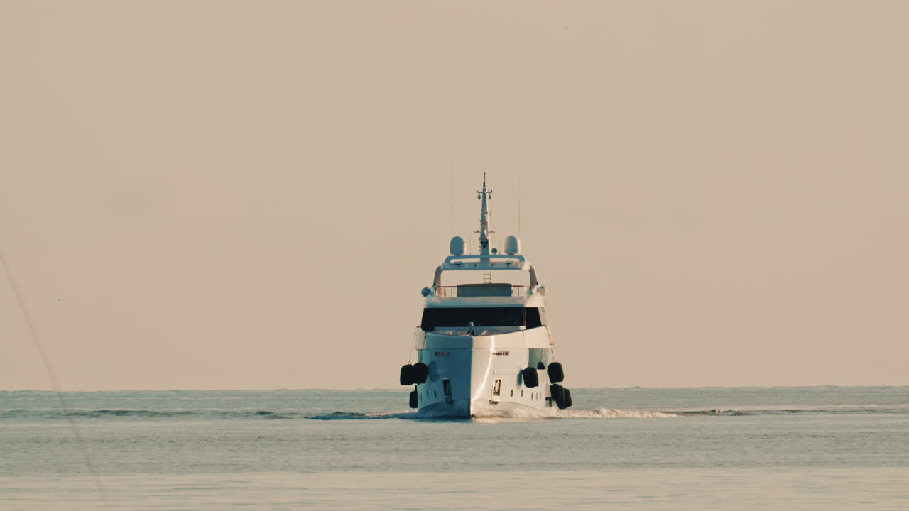 Vista frontale di un lussuoso yacht a motore che naviga lentamente in acque calme del Mediterraneo, con una boa di navigazione visibile nelle vicinanze