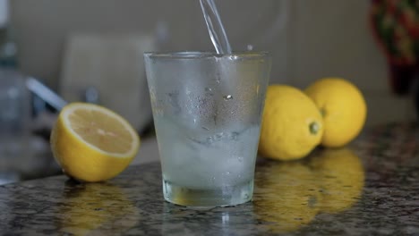 Pouring-and-splashing-lemonade-with-ice-cubes-and-seeds-into-glass