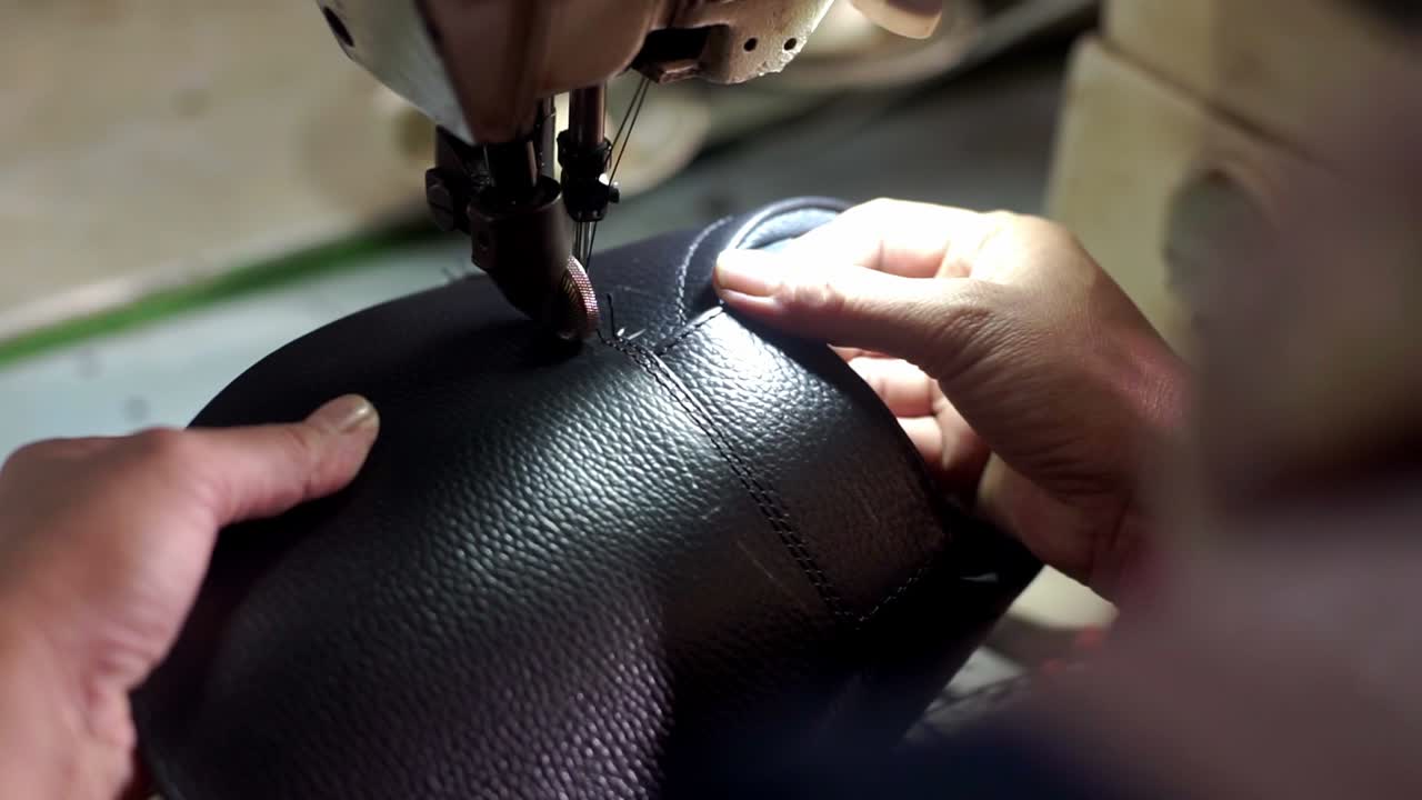 primer plano de un zapatero que hace un mocasin con una máquina de coser