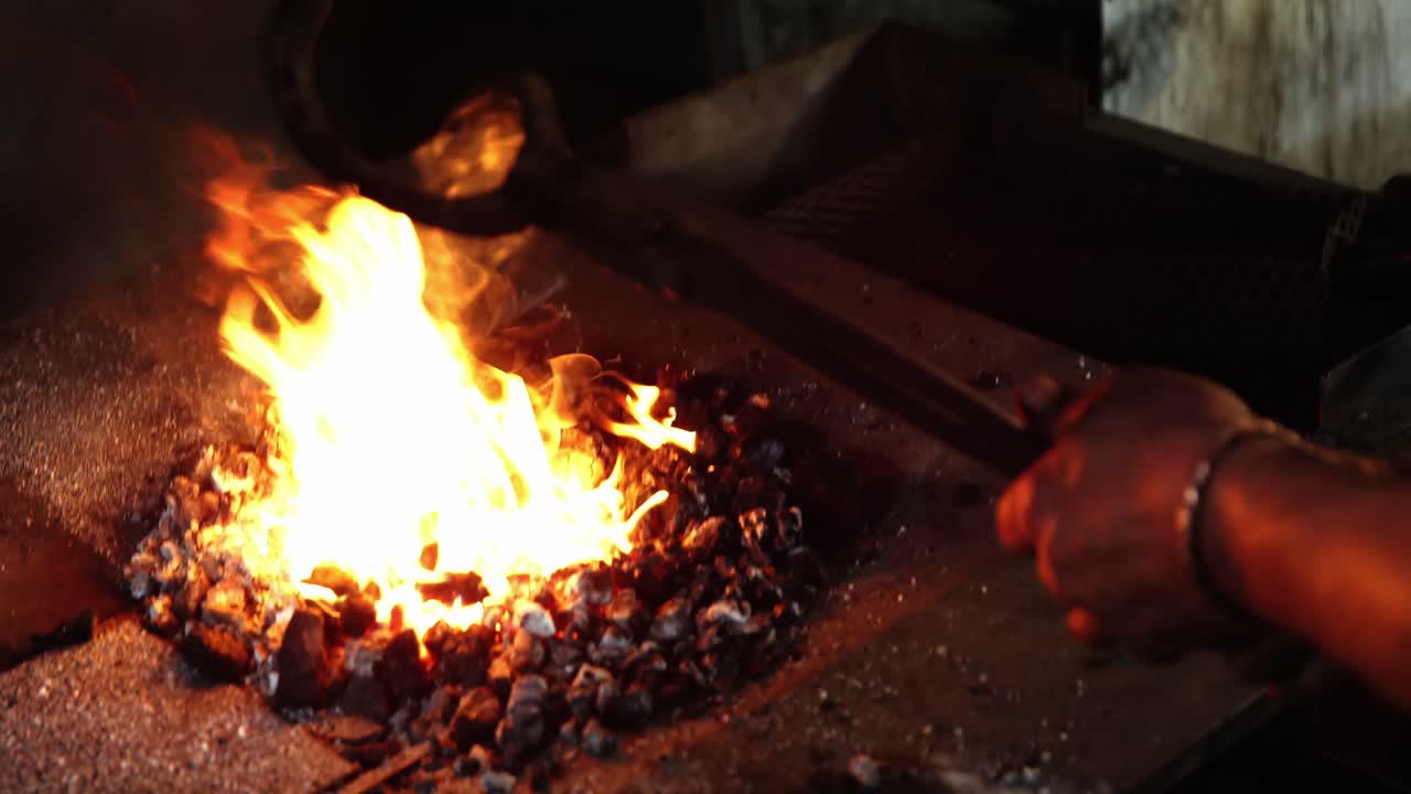 la mano del herrero calentando una herradura en el fuego