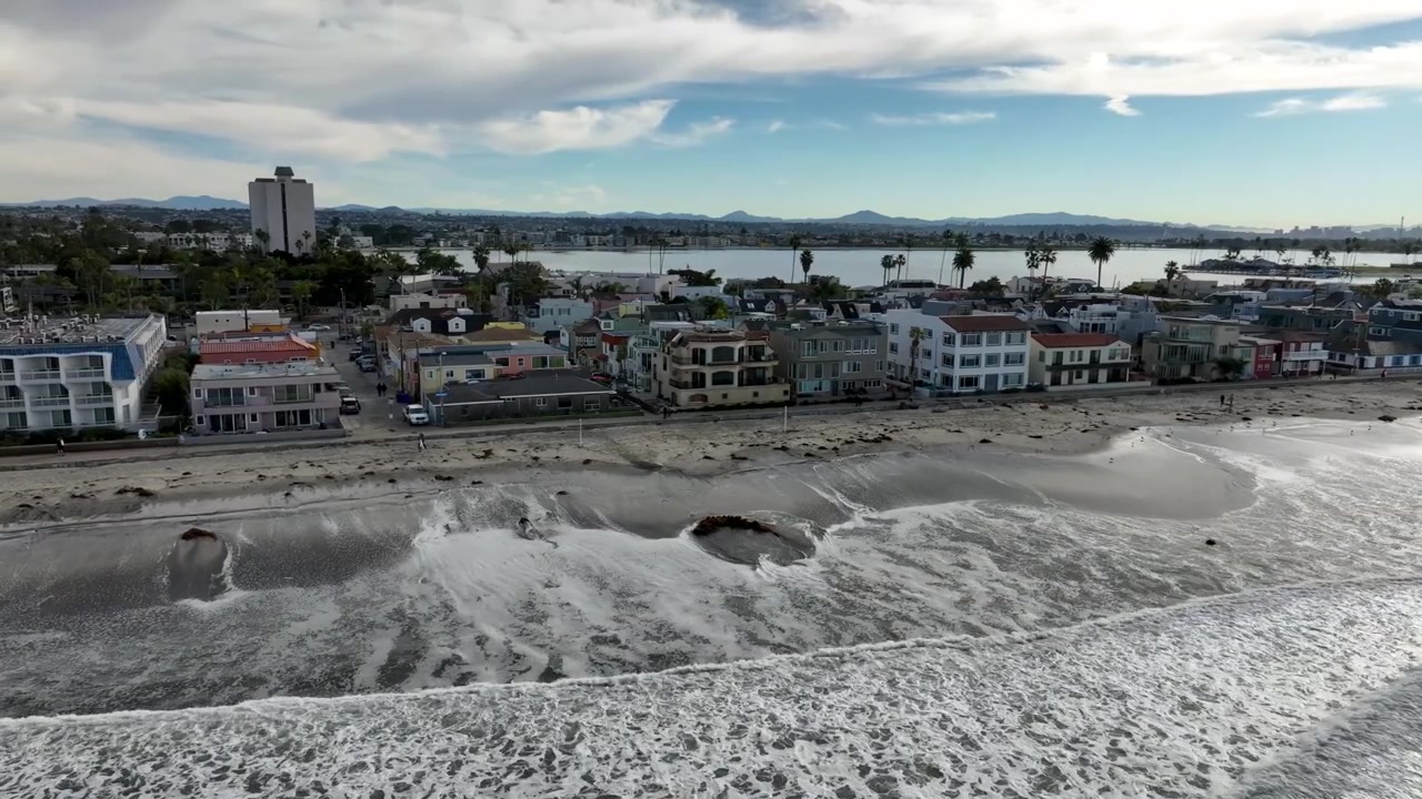 Maree eccezionali di mattina in una giornata nuvolosa nel quartiere costiero di Pacific Beach a San Diego. Ripresa aerea orbitante.