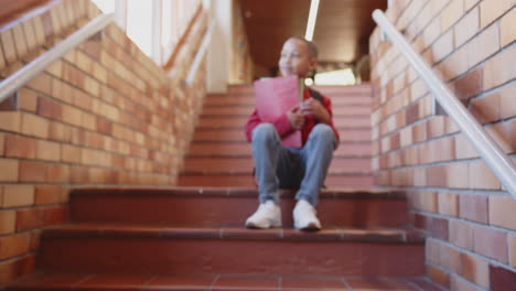 sitting on school stairs, boy holding folder and smiling, enjoying break time
