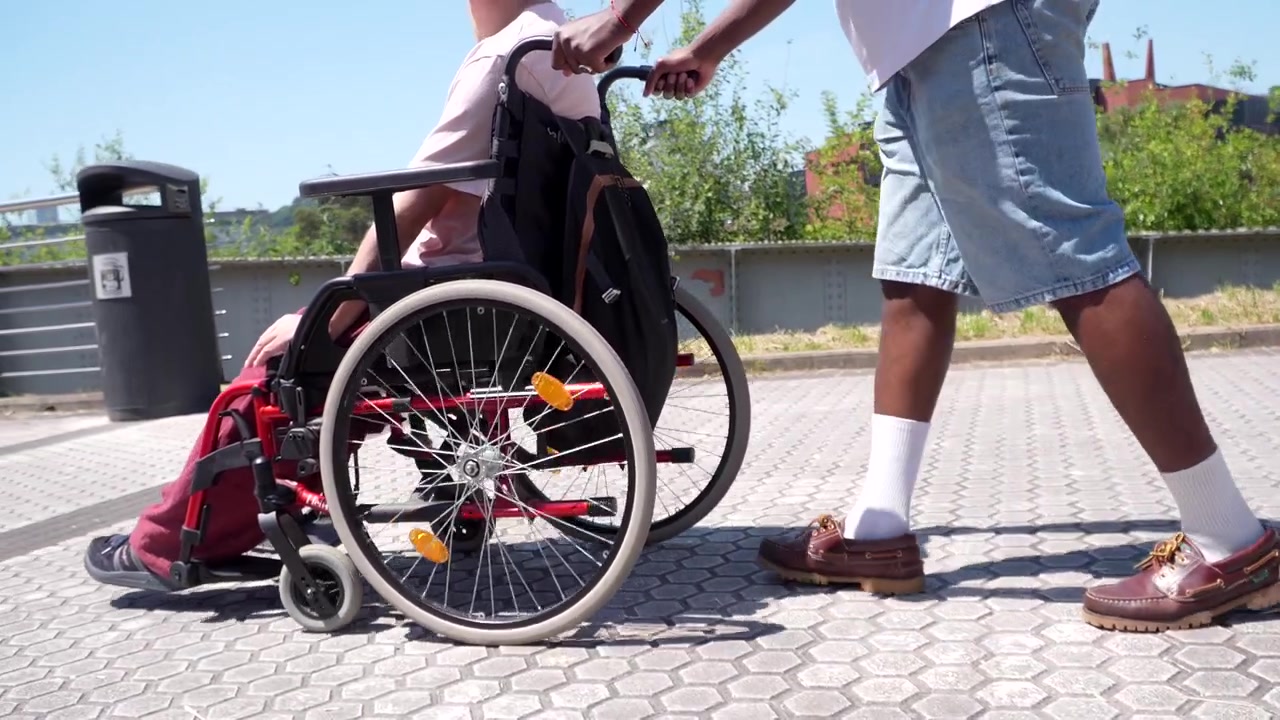 Jeune homme poussant un ami en fauteuil roulant en extérieur