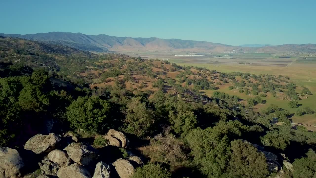 zoom de muñeca aérea, valle verde rodeado de montañas al pie de las colinas en california
