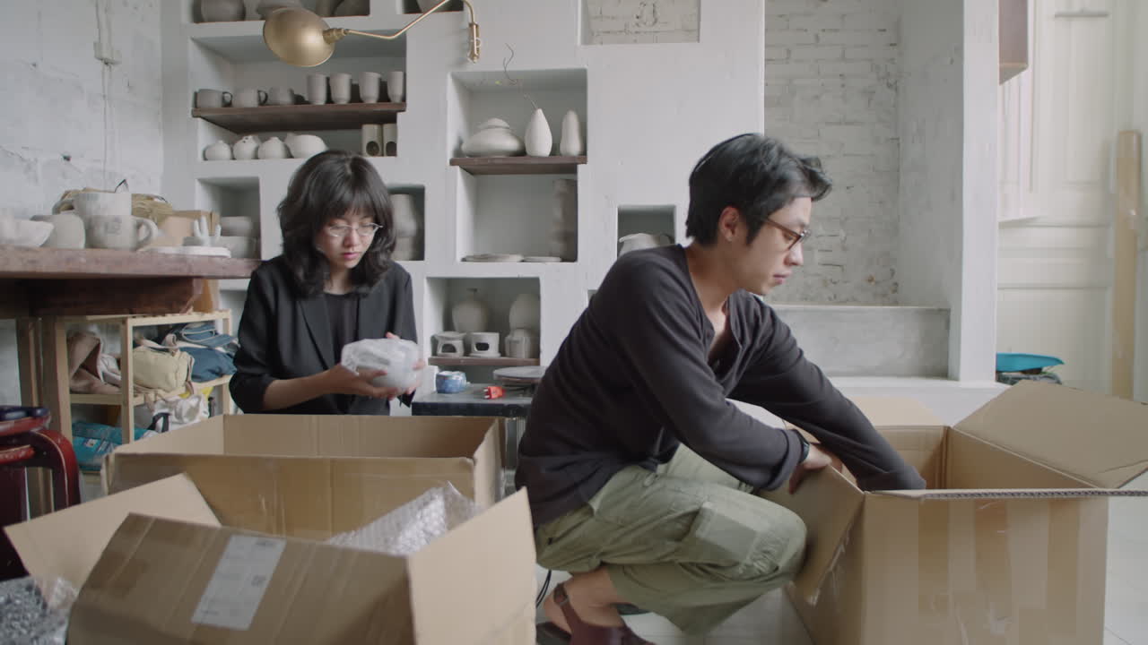 Young Asian Pottery Workers Packing Ceramics into Boxes