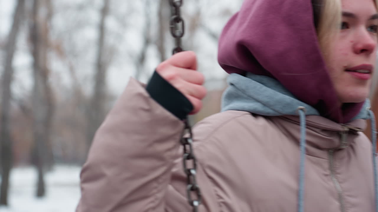 균형을 위해 등반하는 동안 성인이 스 체인을 잡는 클로즈업, 후디와 함께 따뜻한 겨울 재을 입고, 멀리 보케 조명과 사람들의 희미한 실루을 특징으로하는 눈이 흐릿한 배경