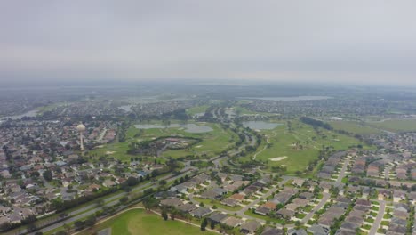 High-flying-aerial-drone-shot-slowly-flying-over-The-Villages,-Florida-with-birds-circling-above-and-a-cloudy,-dreary-sky