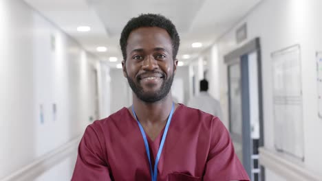 unaltered portrait of happy african american male nurse in hospital corridor in slow motion