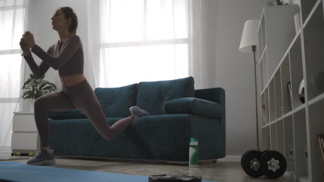 young woman is using couch like sport equipment during home training at weekend doing crouching in living room healthy and sporty lifestyle at self-isolation