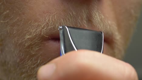 extreme close up of a young scandinavian male trimming his beard