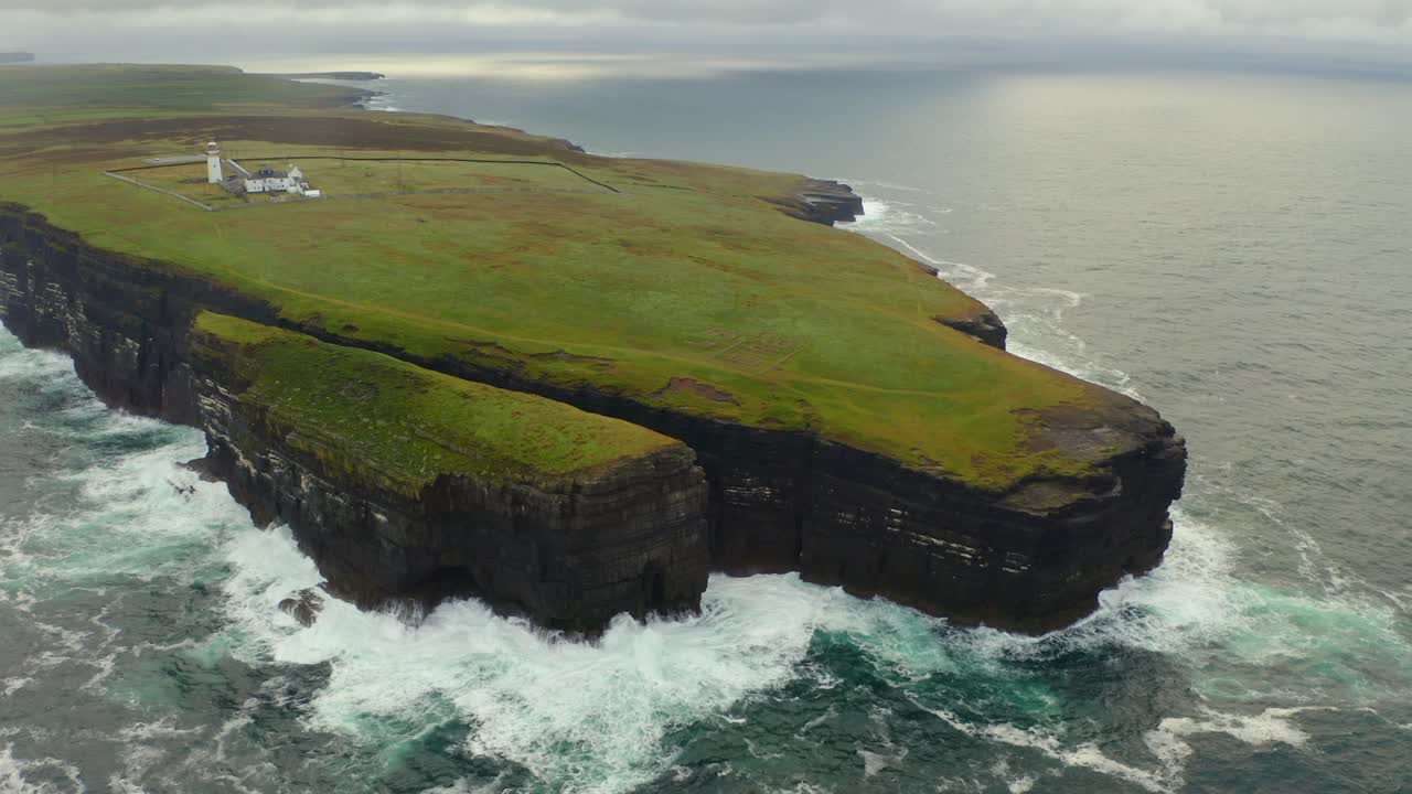 vasta órbita aérea de la península de loop head, condado de clare, con olas que se estrellan contra los acantilados