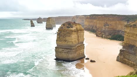 aerial view of the twelve apostles with waves crashing against limestone stacks under cloudy skies at port campbell, australia