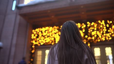 mujer caminando por la ciudad con luces de navidad