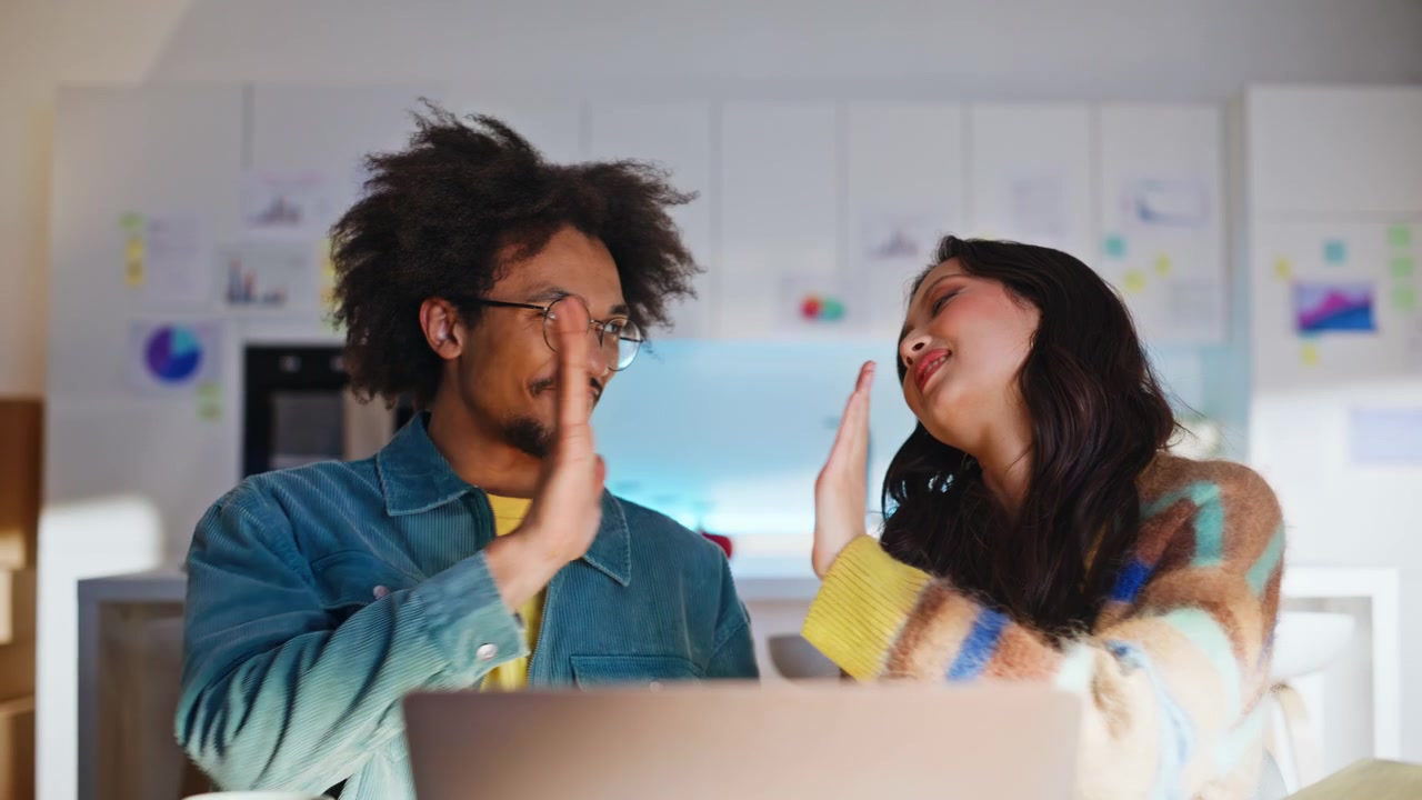 Freelancers high five celebrating good news. Diverse team laptop office success.