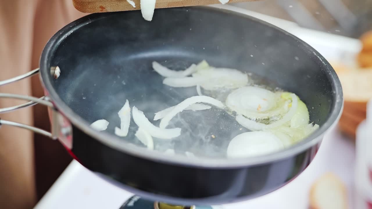 Close up of onions sizzling in oil on outdoor stove during summer picnic cookout