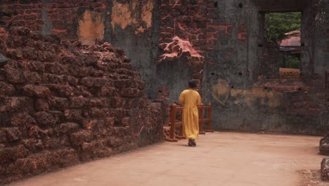 Woman-in-a-yellow-dress-walking-through-ancient-ruins-with-weathered-stone-walls