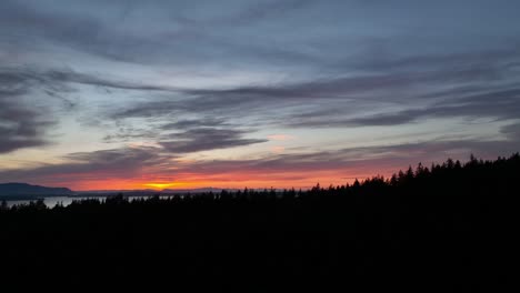 Toma-Aérea-Que-Se-Eleva-Por-Encima-De-La-Línea-De-árboles-En-El-Arboreto-De-Sehome-Hill-Para-Revelar-La-Puesta-De-Sol-Sobre-La-Bahía-De-Bellingham