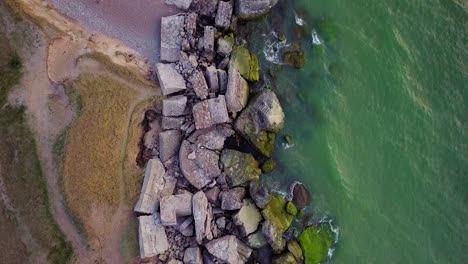 aerial birdseye view of abandoned seaside fortification buildings at karosta northern forts on the beach of baltic sea in liepaja, latvia, calm sea, wide drone shot moving forward