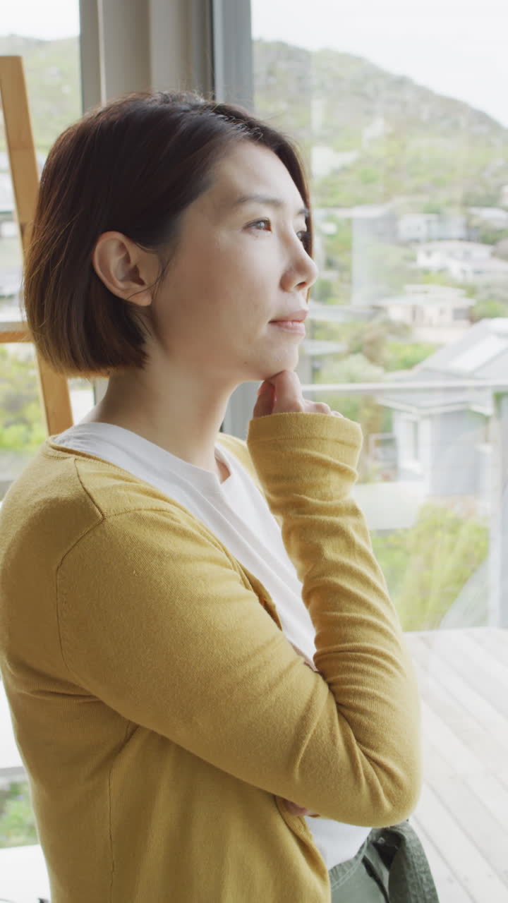 아시아 여성이 을 만지고 창문에서 혼자 생각하는 수직 비디오
