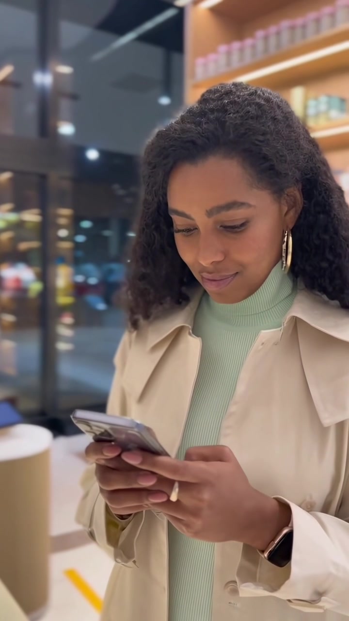 Ung kvinde bruger smartphone i moderne butik