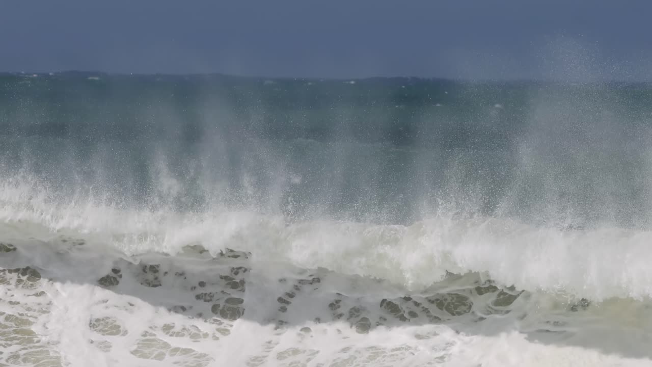 Close-up view of ocean waves with mist rising, showcasing dynamic water movement and frothy surf.