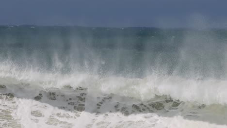 close-up view of ocean waves with mist rising, showcasing dynamic water movement and frothy surf.