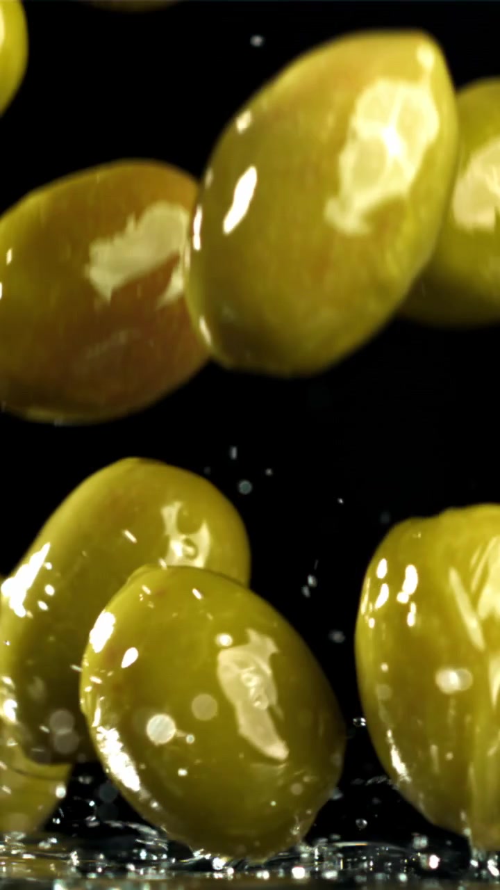 Olive verdi fresche che cadono e schizzano al rallentatore