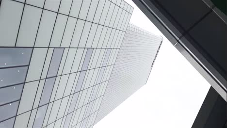revelando un edificio muy alto y limpio desde debajo del puente enorme edificio de vidrio masivo oficina de lujo lo mejor del mundo alcanzando hacia el cielo cielo nublado londres lugar de trabajo de ritmo rápido