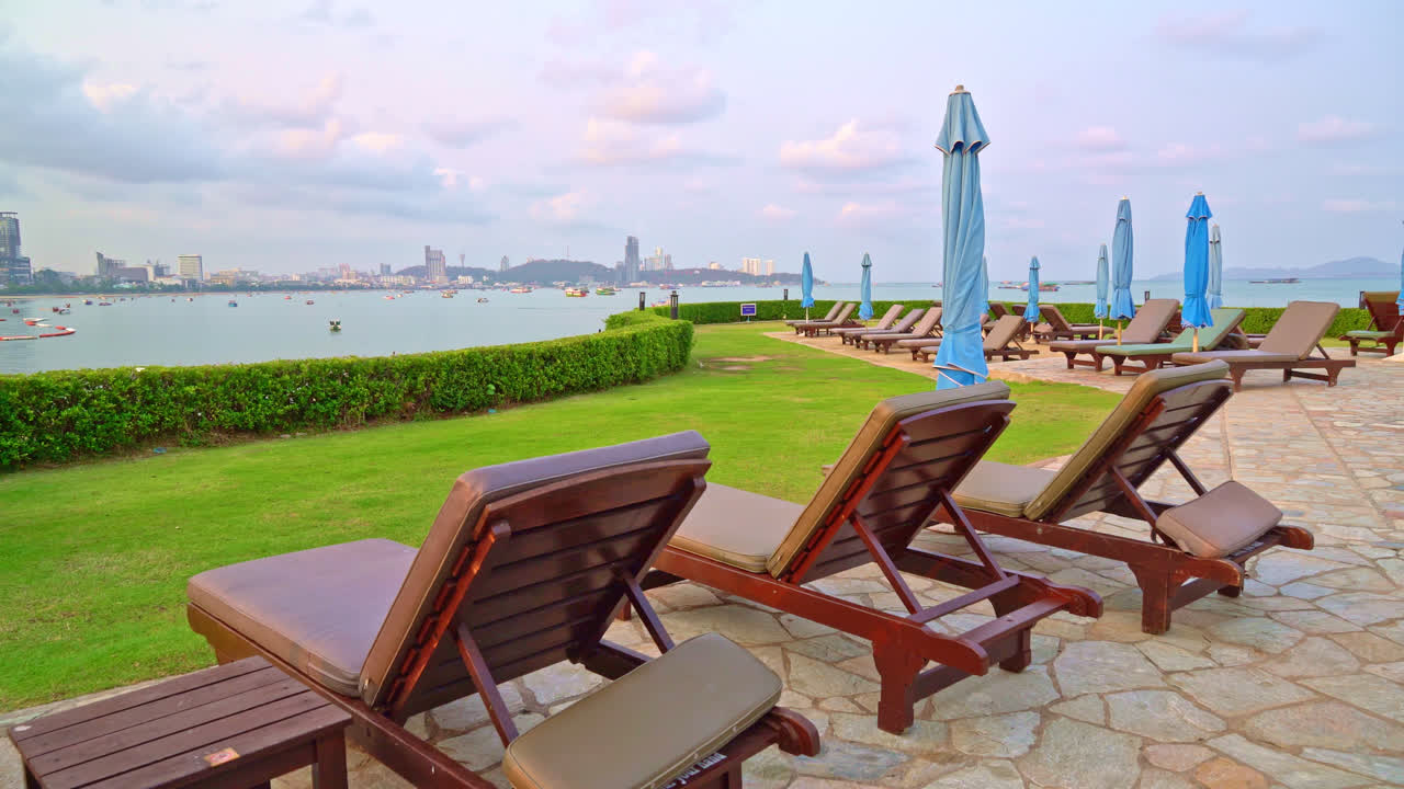 Beach scene with chaise lounges, umbrellas, and cityscape