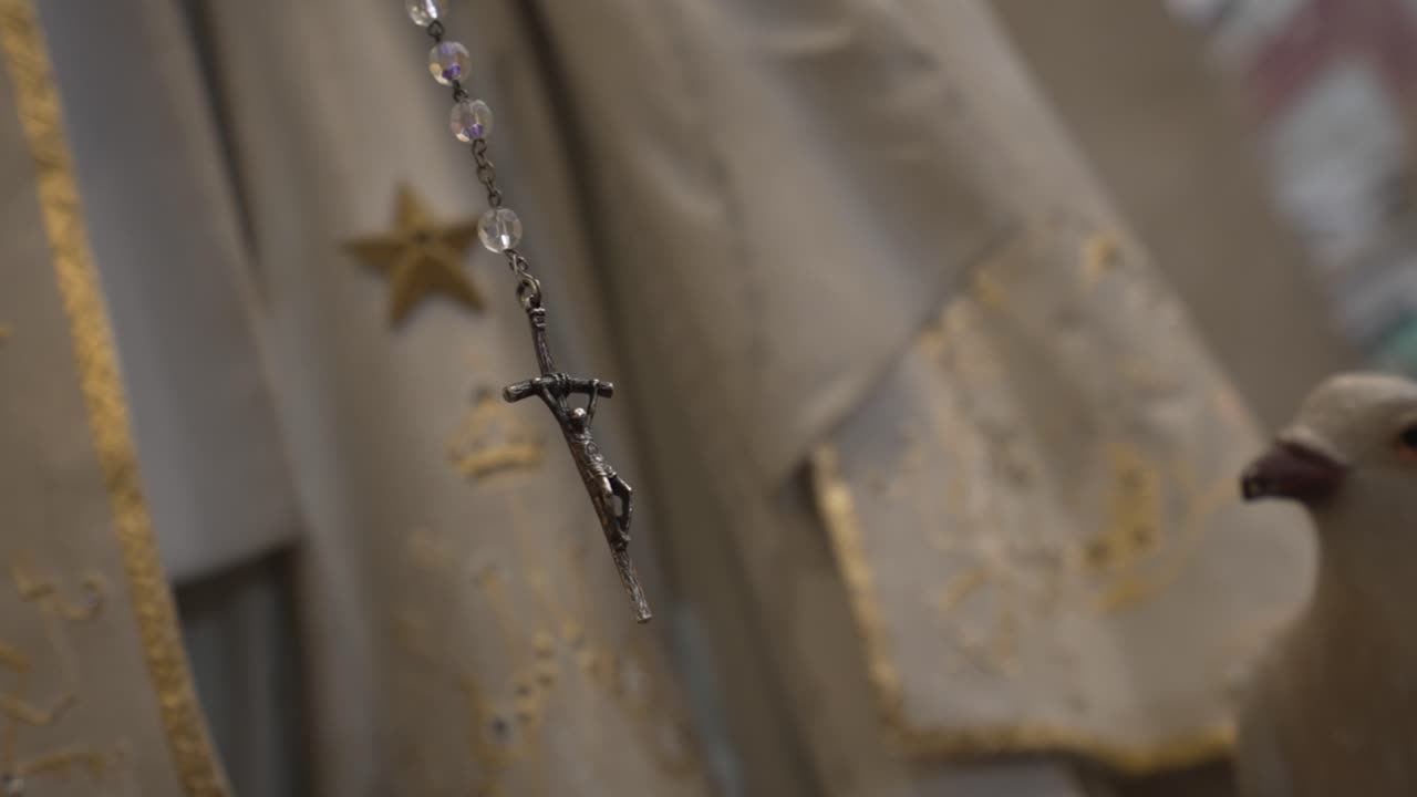 Close up of rosary crucifix against ornate vestments, symbolizing faith and devotion