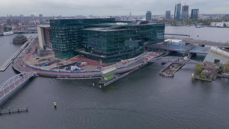 modern corporate building next to the amsterdam canal aerial drone shot