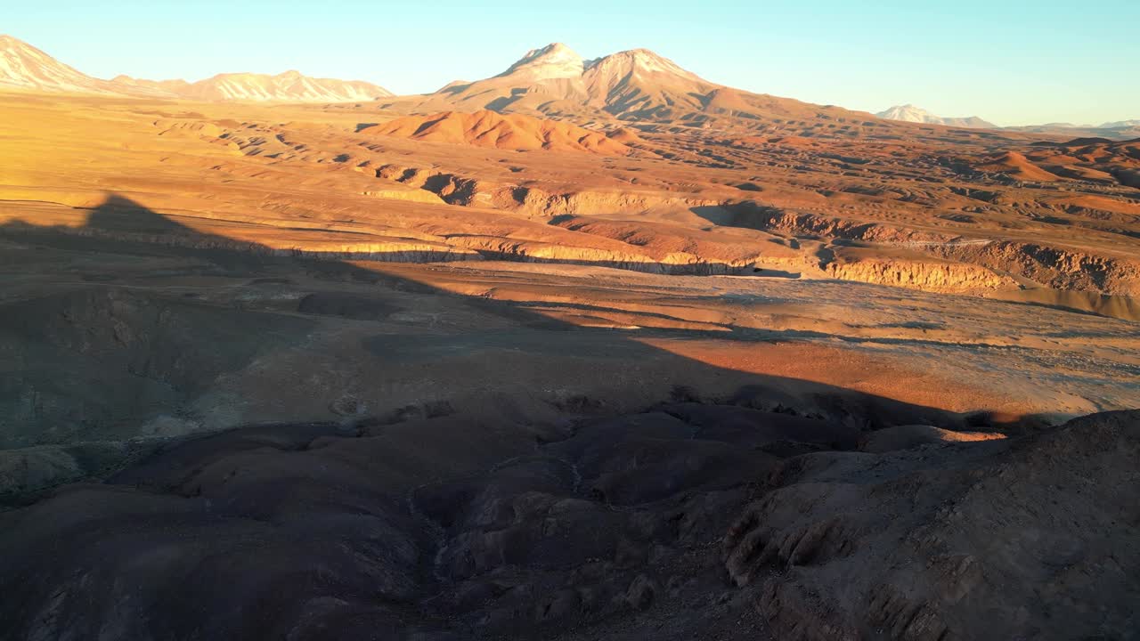 Expansive 4K flyover highlighting San Pedro’s desert mountains glowing warmly beneath the Andes at sunset