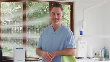 Portrait-of-smiling-caucasian-male-dentist-looking-at-camera-at-modern-dental-clinic