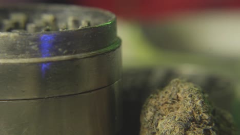 panning shot from a cannabis or marijuana bud to a weed grinder used for making the reefer fine enough to roll into a joint