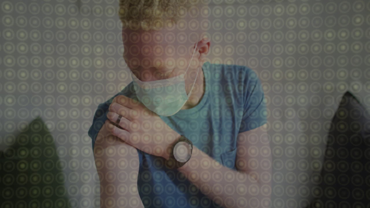 Wearing mask, person touching shoulder against circular animation pattern background