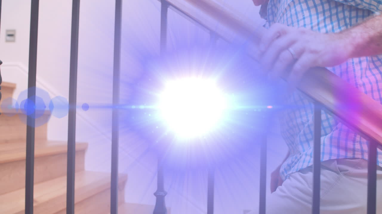 계단 위로 걸어가는 바니스터를 들고 있는 고위 남자의 중간 부분을 가로지르는 빛의 애니메이션