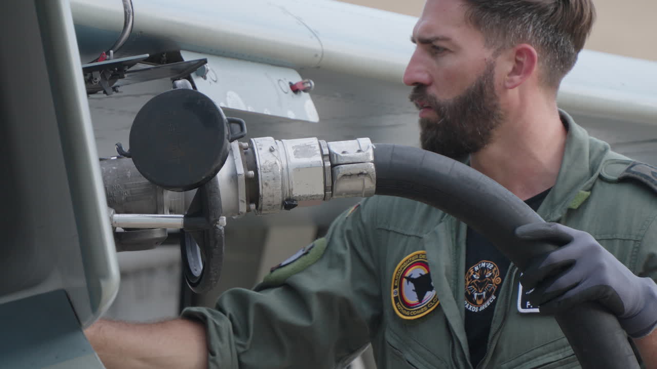 Military Mechanic Refueling a Fighter Jet on the Airfield
