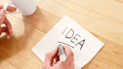 man having a cup of black coffee while writing on piece of paper