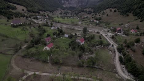 video with descriptive panning drone advancing over the lepushë valley above the lëpusha river, the sh20 in albania, you can see small houses of the town, somewhat cloudy sky and the dry river