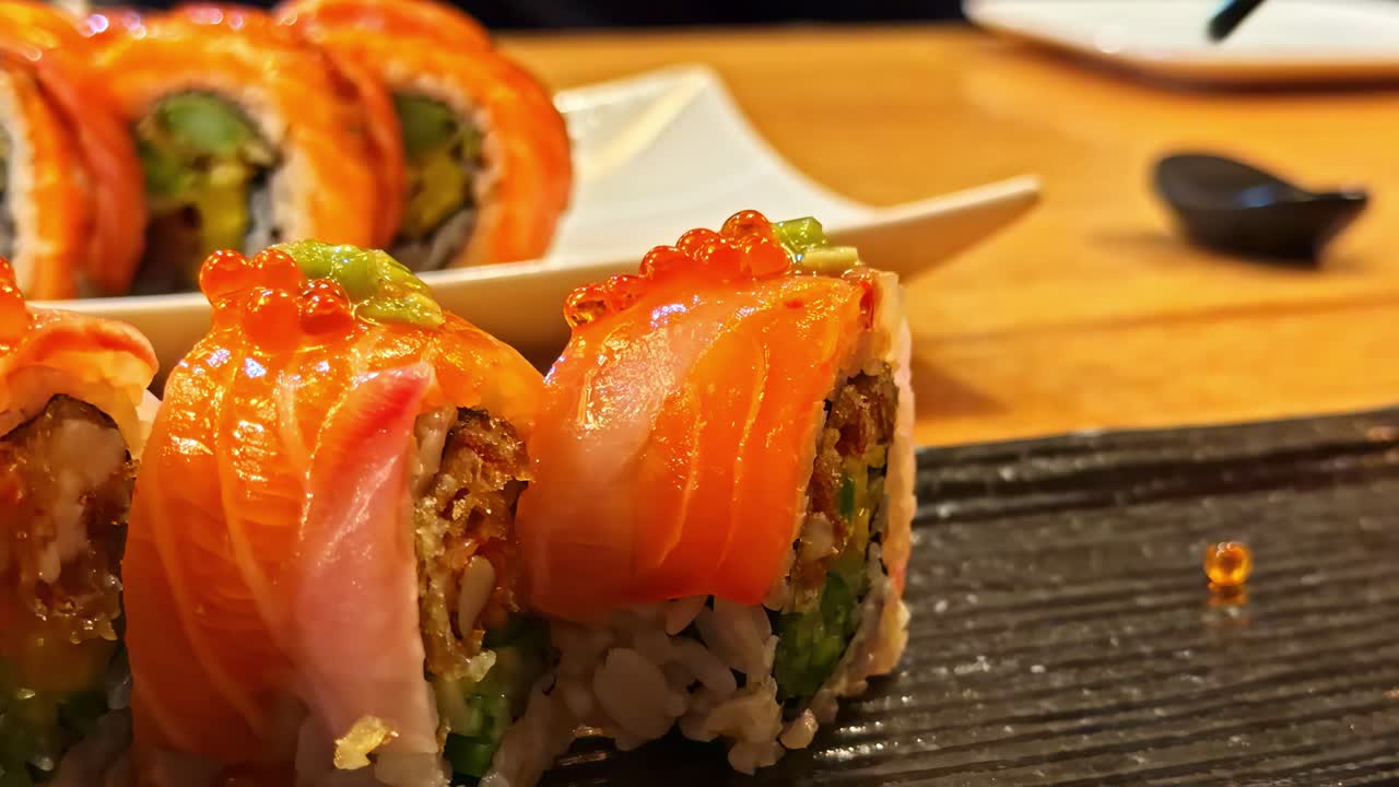 Nahaufnahme von Sushi-Lachsrollen, serviert auf einem schwarzen Teller in einem japanischen Restaurant