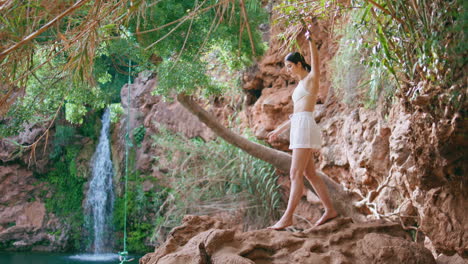 serene model stepping cliff volcanic rocks at jungles. woman at paradise lagoon