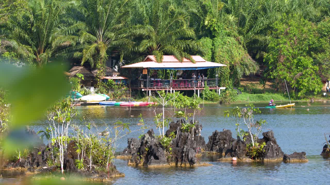 Toàn cảnh mọi người chèo thuyền kayak trên hồ nhiệt đới yên bình gần các khối đá vôi.