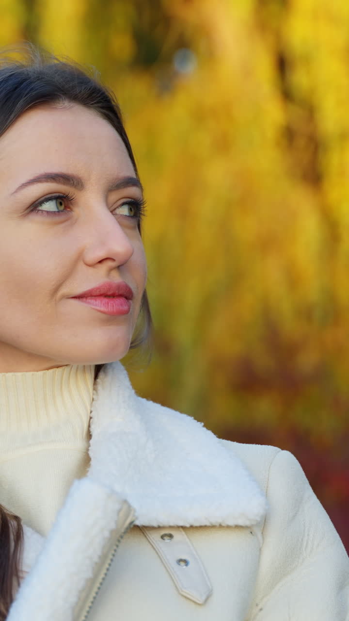 Attractive cheerful woman wearing coat. Portrait of young lady in autumn background. Vertical video