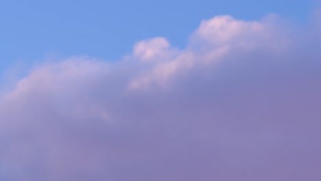 abstract handheld closeup of clouds with purple hues in a bright blue skyline