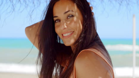 Mujer-Bajo-Una-Sombrilla-De-Playa-Sonriendo-A-La-Cámara